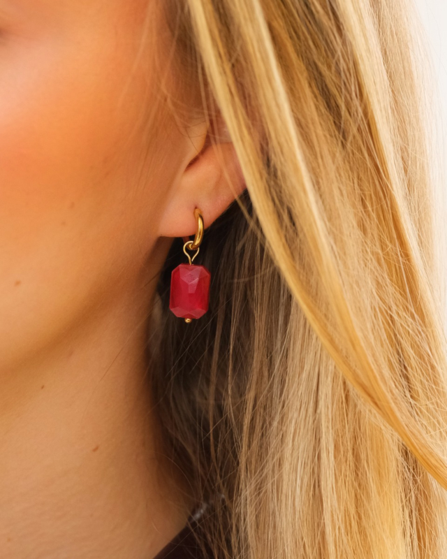Model draagt gouden oorringetjes met rode steen