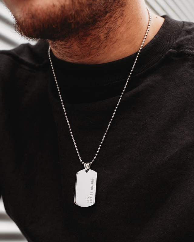 Man draagt zilveren dog tag ketting