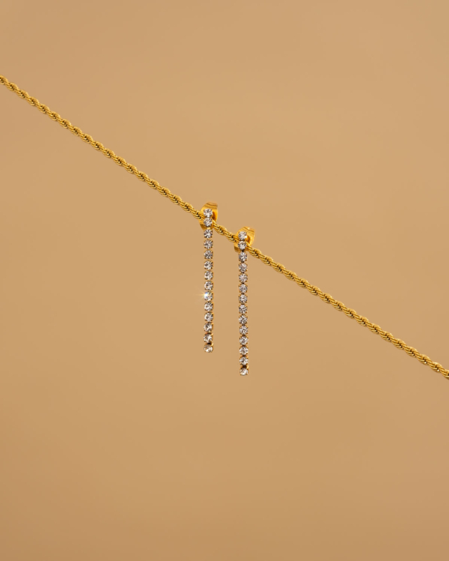 shiny tennis earrings op beige achtergrond