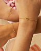 Drie gouden armbandjes om polsen