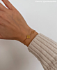 influencer draagt initial armband goudkleurig