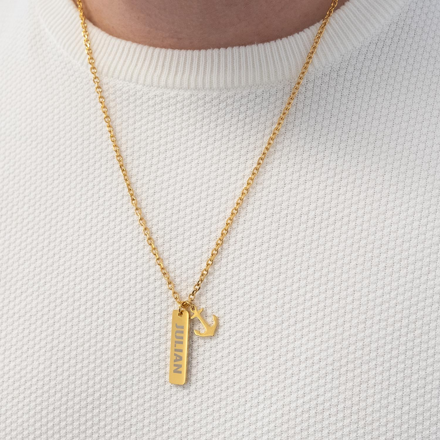 Man draagt gouden ketting met anker om de hals voor een total look