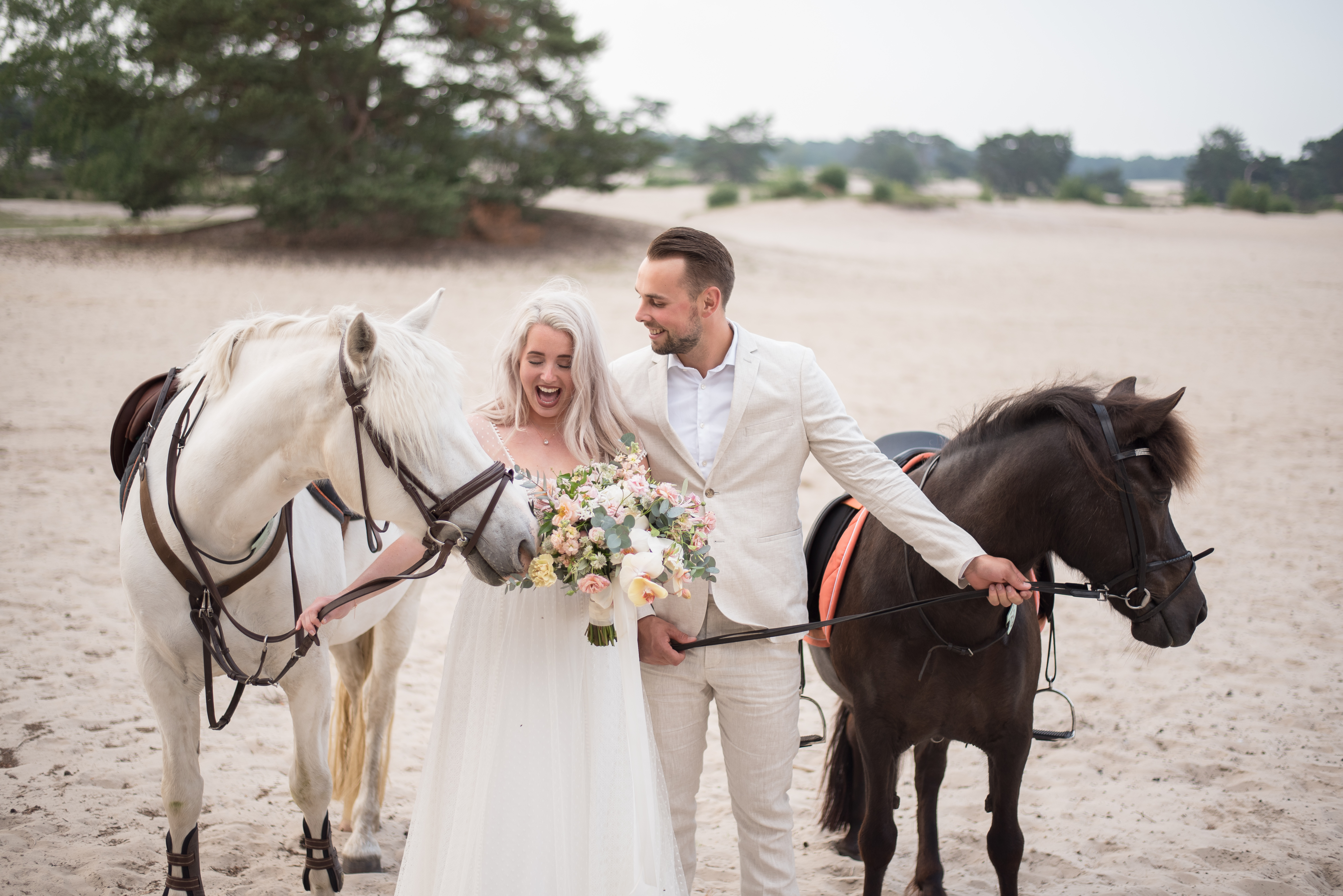 bruidspaar met paarden op het strand