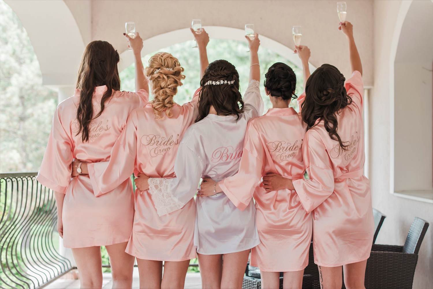 Bruid met vier bruidsmeisjes in kimono's heffen glas champagne