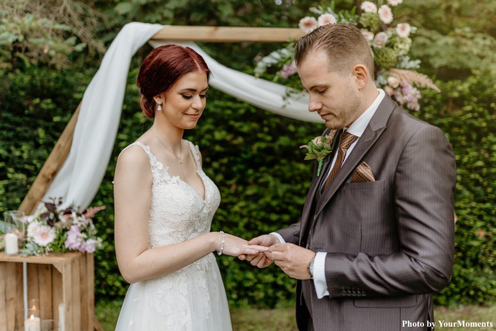 bruid en bruidegom doen trouwringen om tijdens shoot