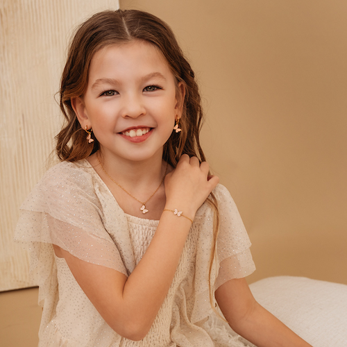 jong meisje met bruin haar draagt vlinder armband, ketting en oorbellen