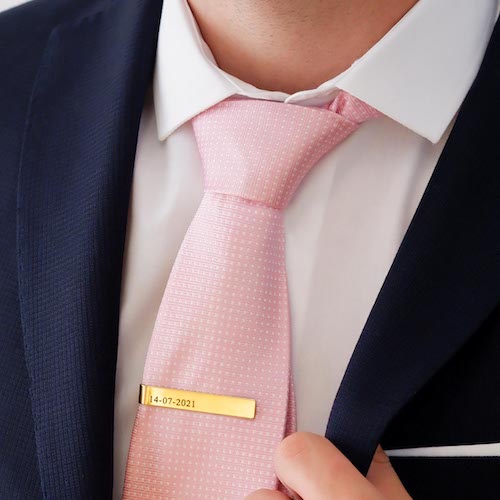 Gouden dasspeld in roze stropdas