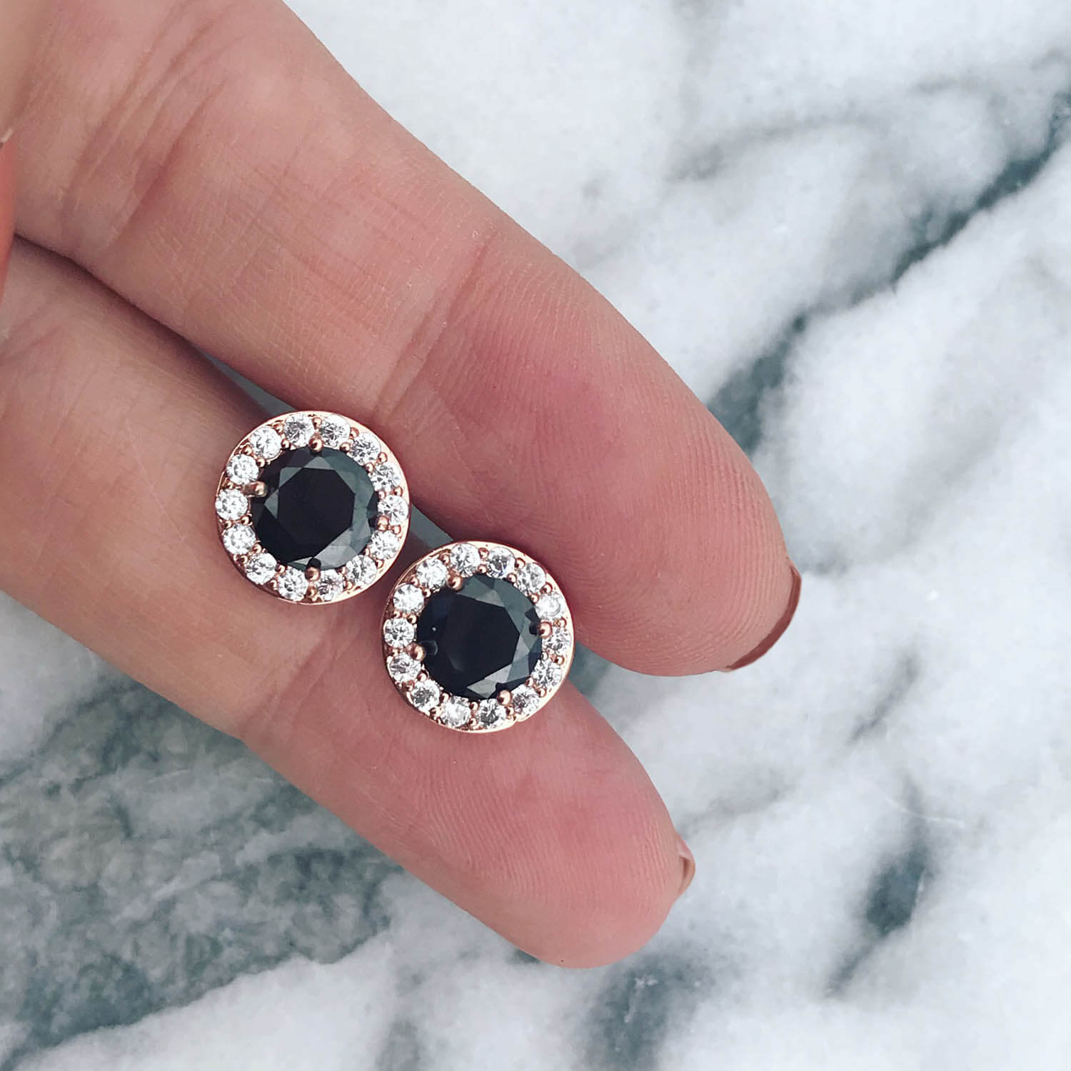 Rose gouden oorbellen op marmer in hand