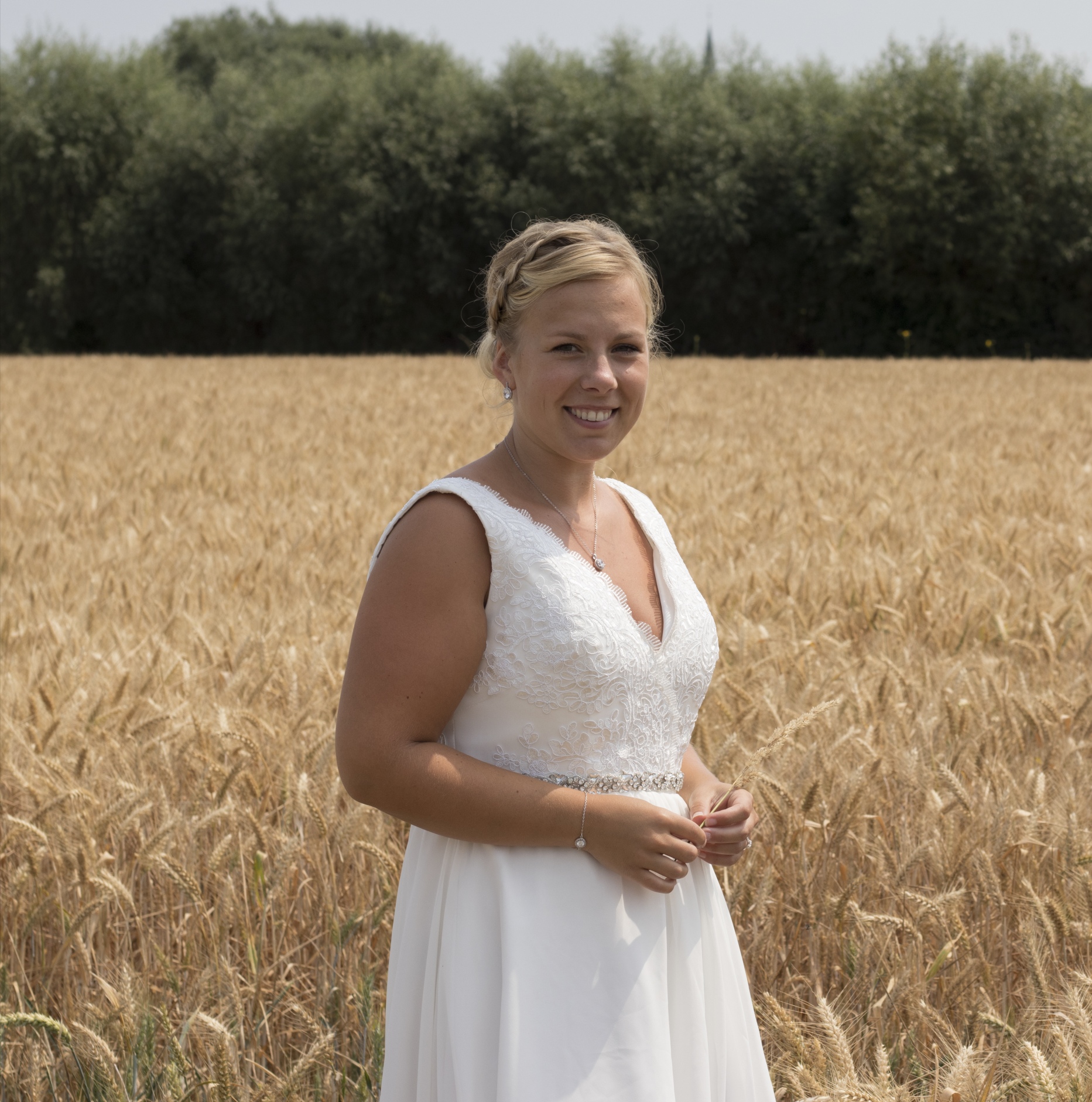 Bruid met trouwjurk en sieraden in weiland