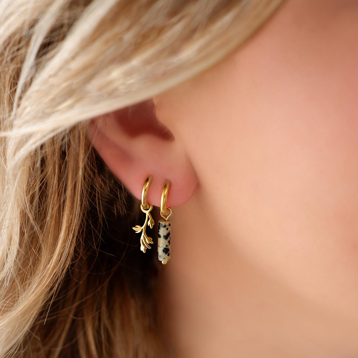 blonde vrouw met gouden oorringetjes steentje en blaadje