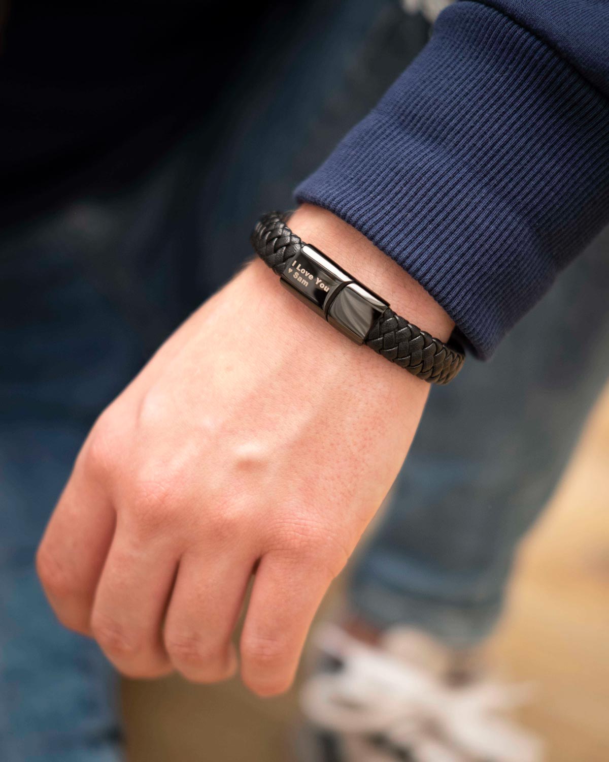 man draagt zwarte leren armband met gravering