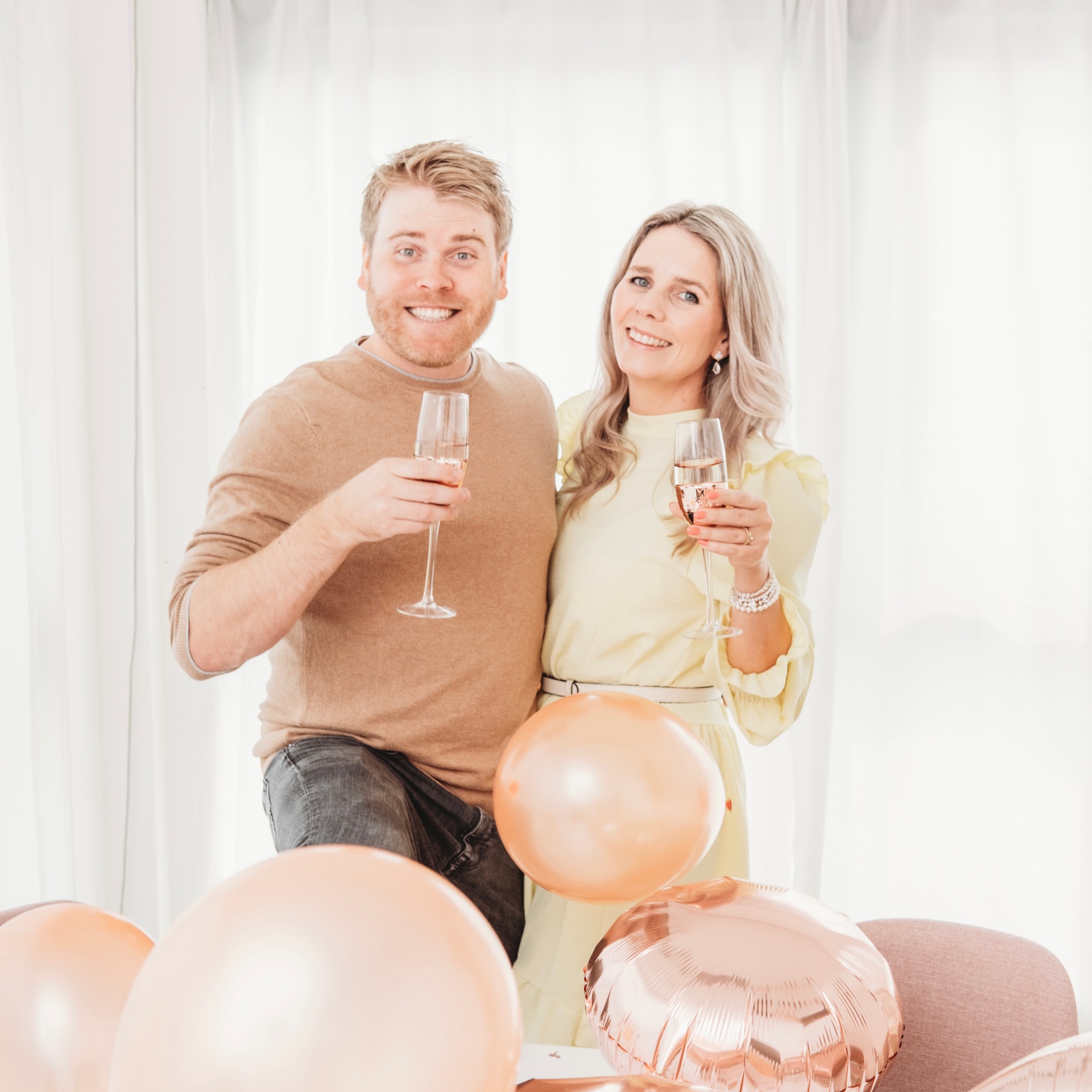 vrolijke man en vrouw met drankje en ballonnen