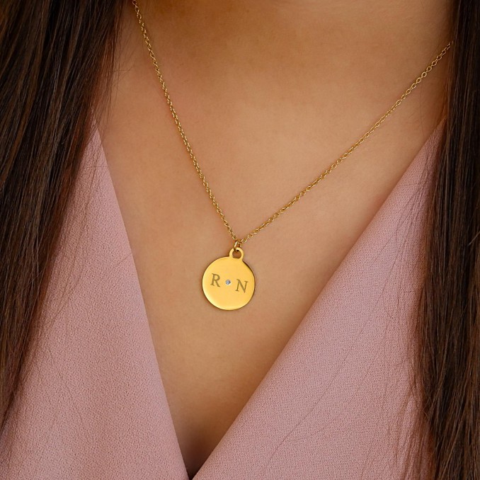 gouden twee initialen ketting bij meisje met bruine haren en roze shirt