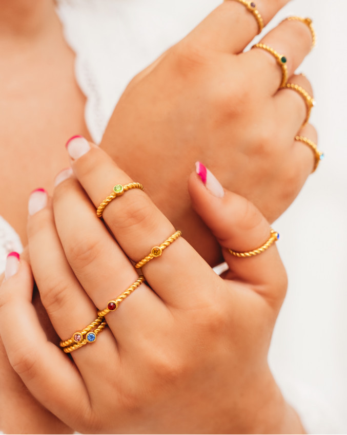 2 handen met allerlei birthstone ringen en roze nagels