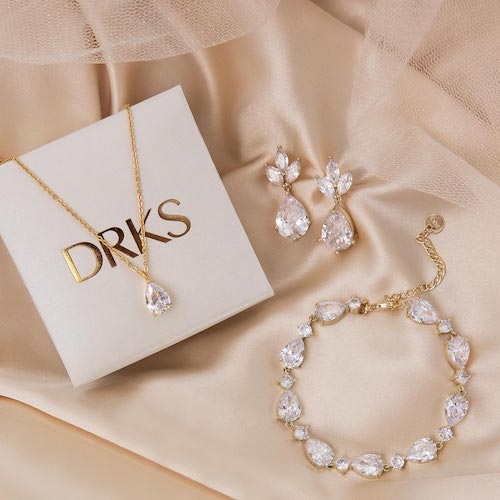 Gouden sieraden set op satijnen deken. De set bestaat uit oorbellen, ketting en een armband